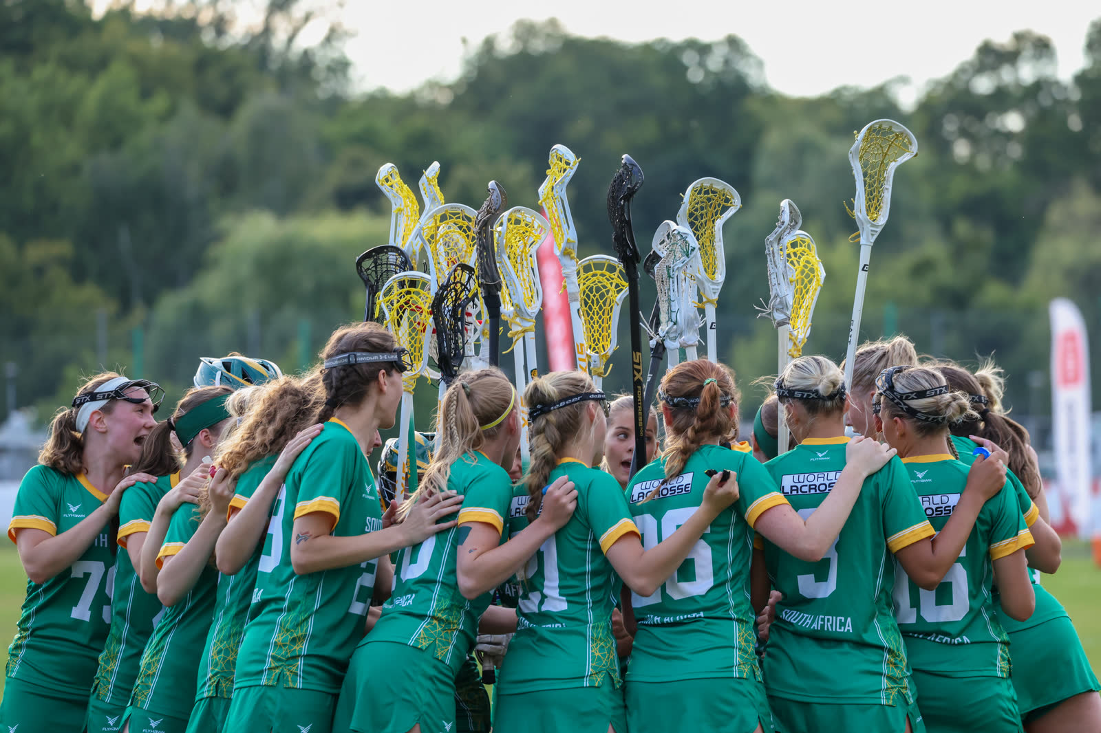 The South Africa women's national team in a huddle with sticks raised